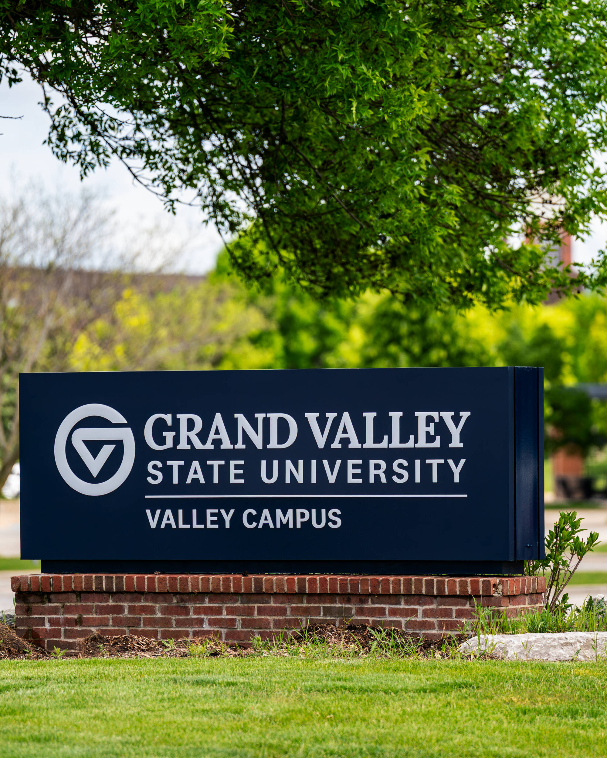 Grand Valley State University Valley Campus sign on a brick base with trees in the background
